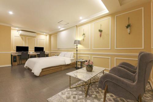 a bedroom with a bed and a desk and chairs at Pandora Hotel in Hwaseong
