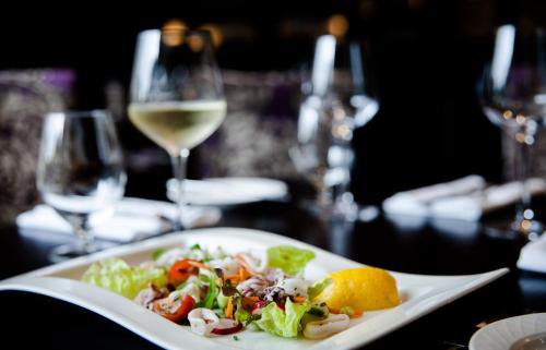 a white plate with a salad and a glass of wine at Trout Hotel in Cockermouth