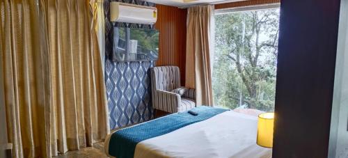 a bedroom with a bed and a window with a chair at Katson Blue Dalhousie in Dalhousie