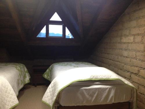 a attic room with two beds and a window at Cabañas Hojarasca in Mineral del Chico