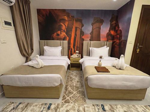two beds in a room with a painting on the wall at Rehana Pyramids View in Cairo