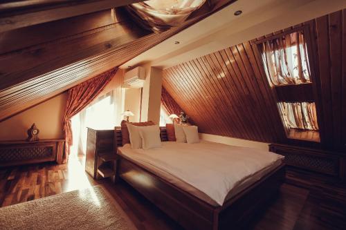 a bedroom with a large bed in a room with wooden walls at Denisa Boutique in Poiana Brasov