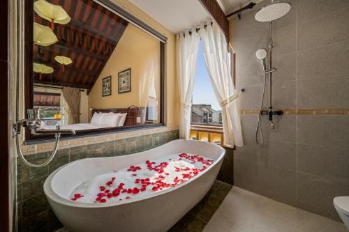 a bathroom with a bath tub covered in red flowers at Solea Boutique Hoi An - Grand Opening April 2026 in Hoi An