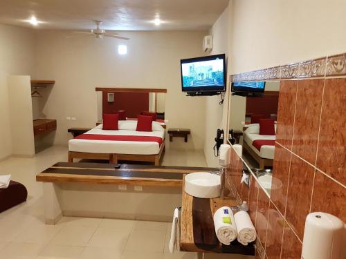 een badkamer met 2 bedden en een tv in een kamer bij Auto Hotel Paraíso Inn in Palenque