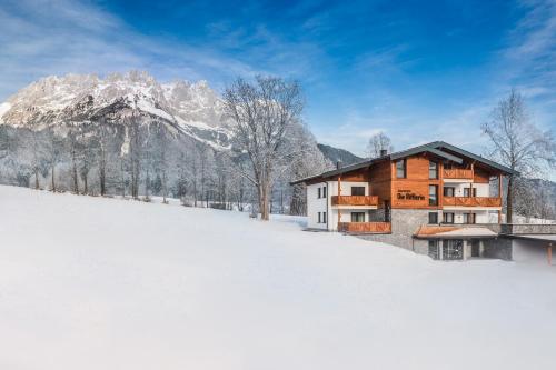 a house in the snow in front of a mountain at Appartements Die Rifflerin in Going
