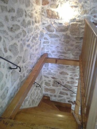 a room with a stone wall and a wooden staircase at Hvar Architect's House in Pitve