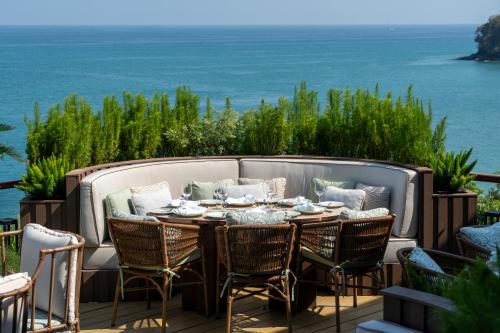 a patio with a table and chairs and the ocean at Cape Panwa Hotel Phuket in Panwa Beach