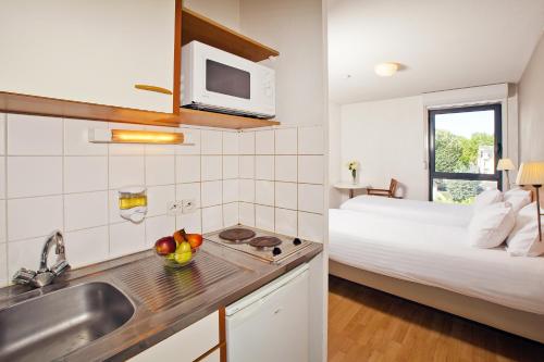 una cocina con fregadero y una cama en una habitación en Séjours & Affaires Orléans Jeanne D'Arc en Orléans
