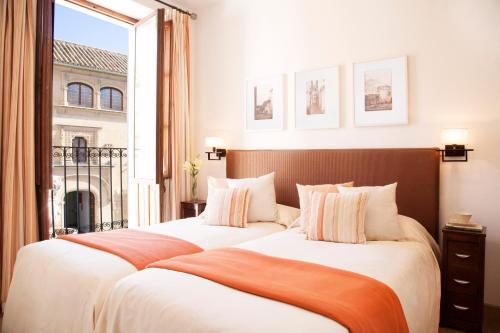 two beds in a hotel room with a window at Las Casas del Potro in Córdoba