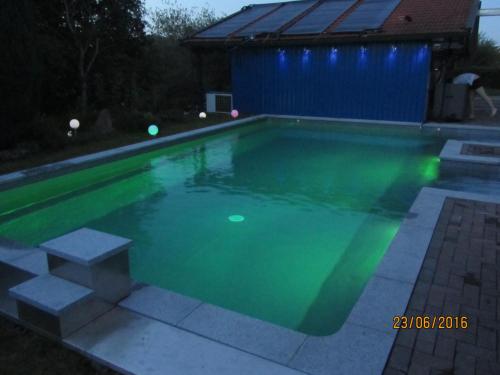 a swimming pool at night with green illumination at Ferienwohnungen Fuchshuber in Neukirchen vorm Wald