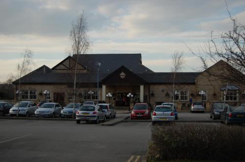 a large building with cars parked in a parking lot at Best Western Plus Pastures Hotel in Doncaster