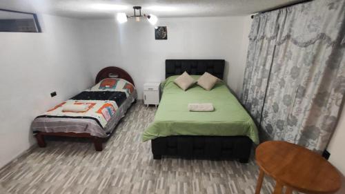 a bedroom with two beds and a table and a chair at Departamento Confortable in Latacunga