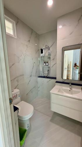 a bathroom with a toilet and a sink and a mirror at Sunrio Beach Hotel Sichon in Ban Plai Thon