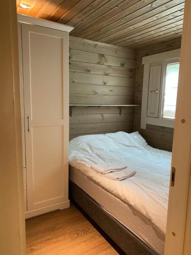 a bed in a room with a wooden wall at Cozy log cabin in Geiranger in Geiranger