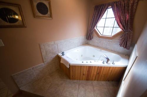 a bathroom with a bath tub with a window at Long Lake Resort in Poteau