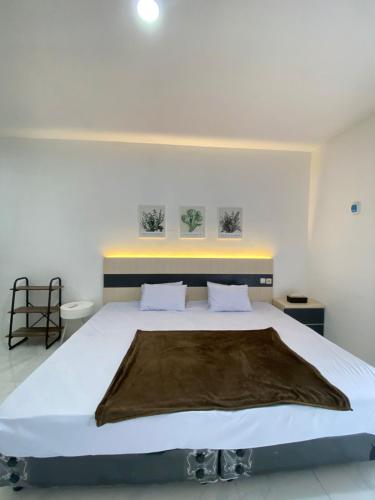 a bedroom with a large bed with a brown blanket on it at Kims Stay Syariah in Jember