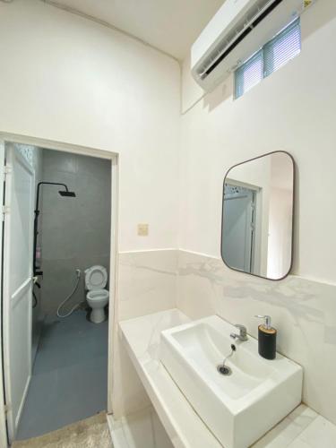 a white bathroom with a sink and a mirror at Kims Stay Syariah in Jember