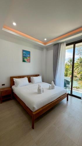 a bedroom with a large bed and a large window at Sunrio Beach Hotel Sichon in Ban Plai Thon