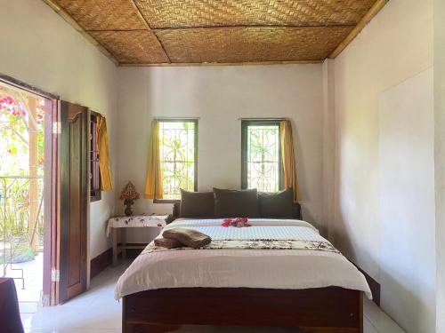 a bedroom with a bed in a room with windows at Kembang Kuning Cottages in Tetebatu