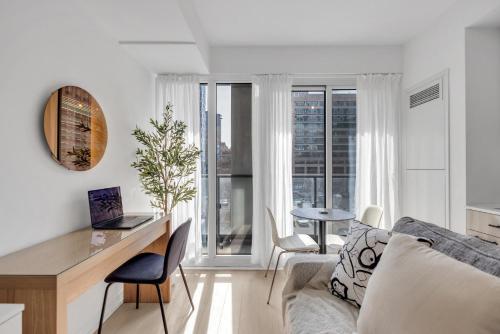 a living room with a couch and a desk with a laptop at Work-Friendly 1BR Suite Steps to Eaton Centre in Toronto