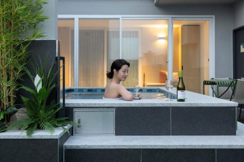 a woman in a bath tub with a bottle of wine at Daejeon Anook Hotel Yuseong Oncheon Station in Daejeon