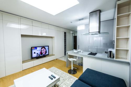 a living room with a couch and a tv on a wall at The Аddress Highvill 1 in Astana