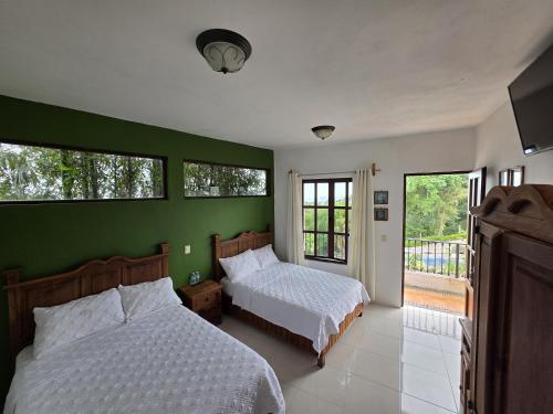 a bedroom with two beds and a green wall at Hotel Magnolia cuetzalan in Cuetzalán del Progreso