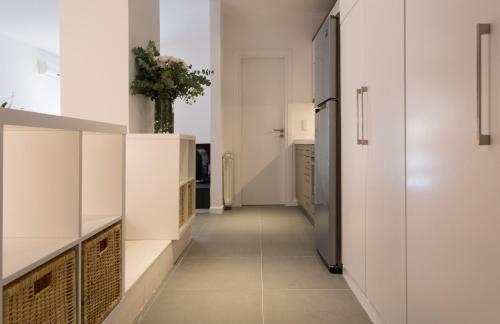 a hallway of a kitchen with white cabinets and a vase at Homz Studios Faliro in Athens