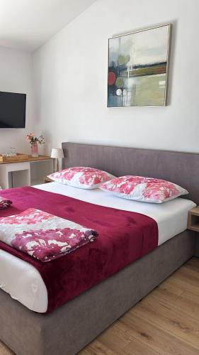 a bedroom with a large bed with red and white pillows at Panorama House Opatija in Donji Rukavac