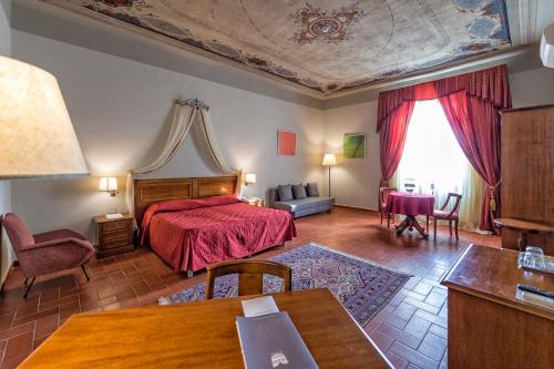a bedroom with a red bed and a couch at Hotel Miravalle in San Miniato