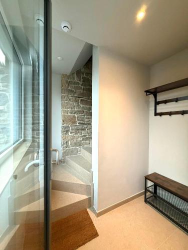 a bathroom with a walk in shower next to a stone wall at Au fil de vos nuits in Lustin