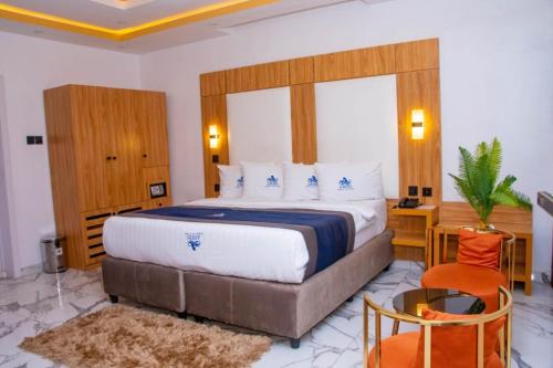 a bedroom with a bed and a table and a chair at Abiis Hotel and Suites in Abeokuta