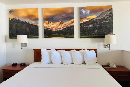 a bedroom with a bed with three paintings on the wall at Days Inn by Wyndham Bishop in Bishop