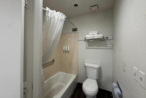 a bathroom with a toilet and a tub and a sink at Days Inn by Wyndham Bishop in Bishop