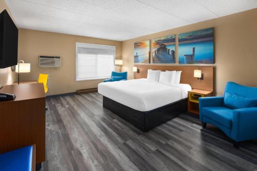 a hotel room with a bed and a blue chair at Days Inn by Wyndham Pierre in Pierre