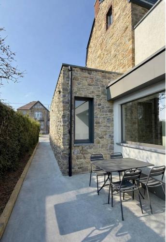 a patio with a table and chairs next to a building at Au fil de vos nuits in Lustin