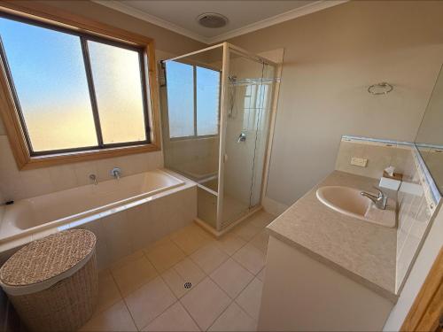 a bathroom with a tub and a shower and a sink at B & B on Yorkes in Edithburgh