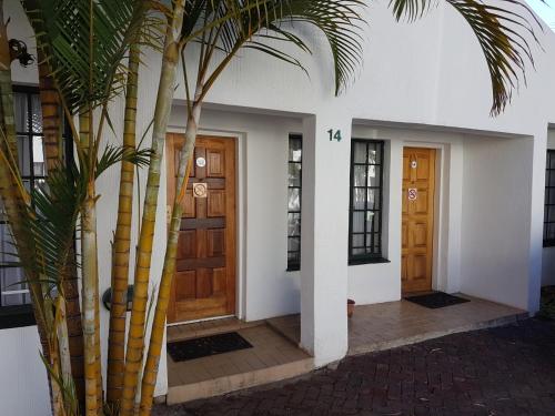 a house with two wooden doors and a palm tree at Eskulaap Hotel in Polokwane