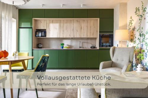a kitchen with green cabinets and a table and a chair at Hufe 9 Gute Stube - Digital Detox und Entschleunigen oder Aktiv-Urlaub in der Natur - Bauernhof Charme trifft modernes Design in Wustrow