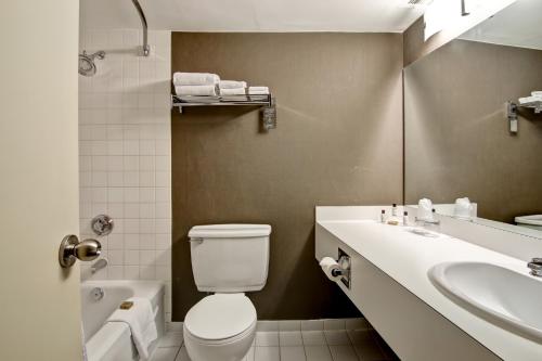 a bathroom with a toilet and a sink and a tub at Chateau Lacombe Hotel in Edmonton