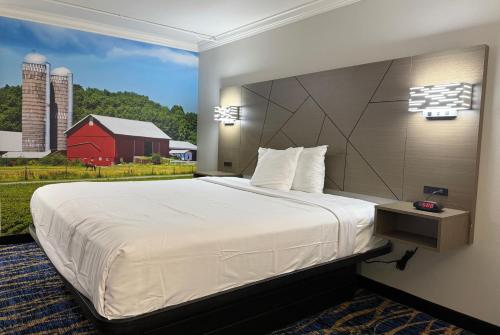 a bedroom with a large bed with a red barn at Travelodge by Wyndham Odessa in Odessa
