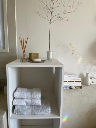 a white shelf with towels and a tree on the wall at L'évidence en Provence in Vachères