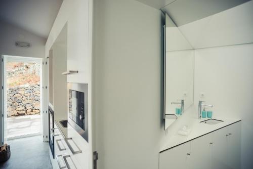 La salle de bains blanche est pourvue d'un lavabo et d'un miroir. dans l'établissement Vigia da Areia, à São Lourenço