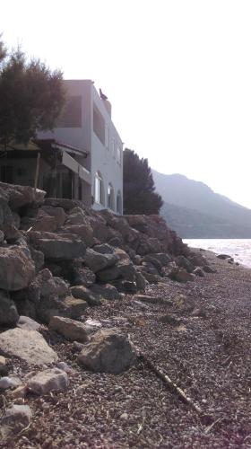 a building on a rocky beach next to the water at Boutique Hotel Tilos Mare in Livadia