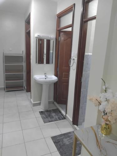 a bathroom with a sink and a mirror and a door at Achievers stays in Kitengela 