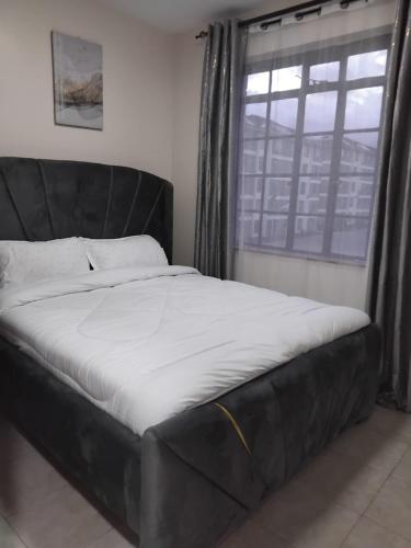 a black bed in a room with a window at Achievers stays in Kitengela 