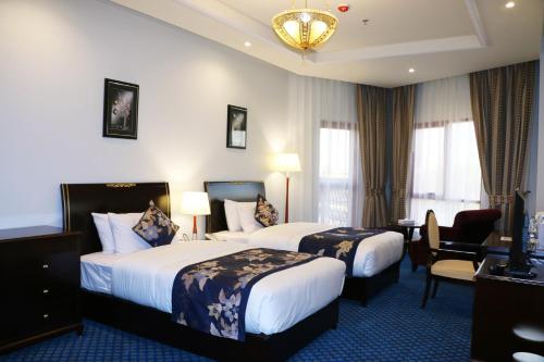 una camera d'albergo con 2 letti e una scrivania di Red Castle Hotel a Sharjah