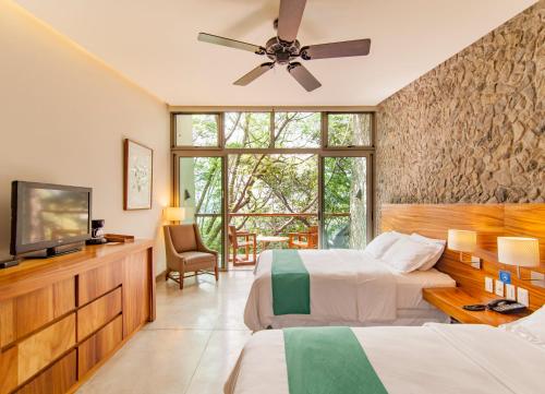 a bedroom with two beds and a flat screen tv at Kawilal Hotel in Amatitlán