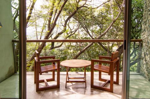 two chairs and a table on a porch with a tree at Kawilal Hotel in Amatitlán