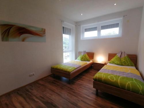 two beds in a room with two windows at Gästehaus Marion Appartements in Sankt Peter ob Judenburg